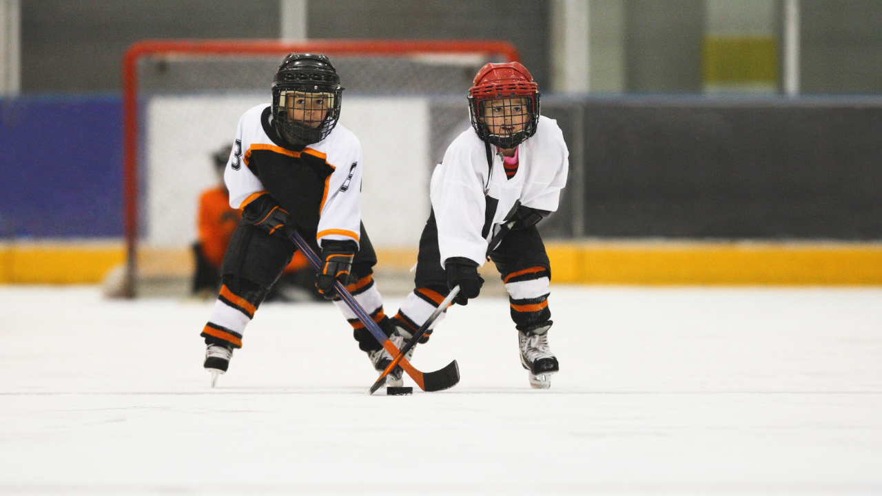 Two young hockey players going after the puck.
