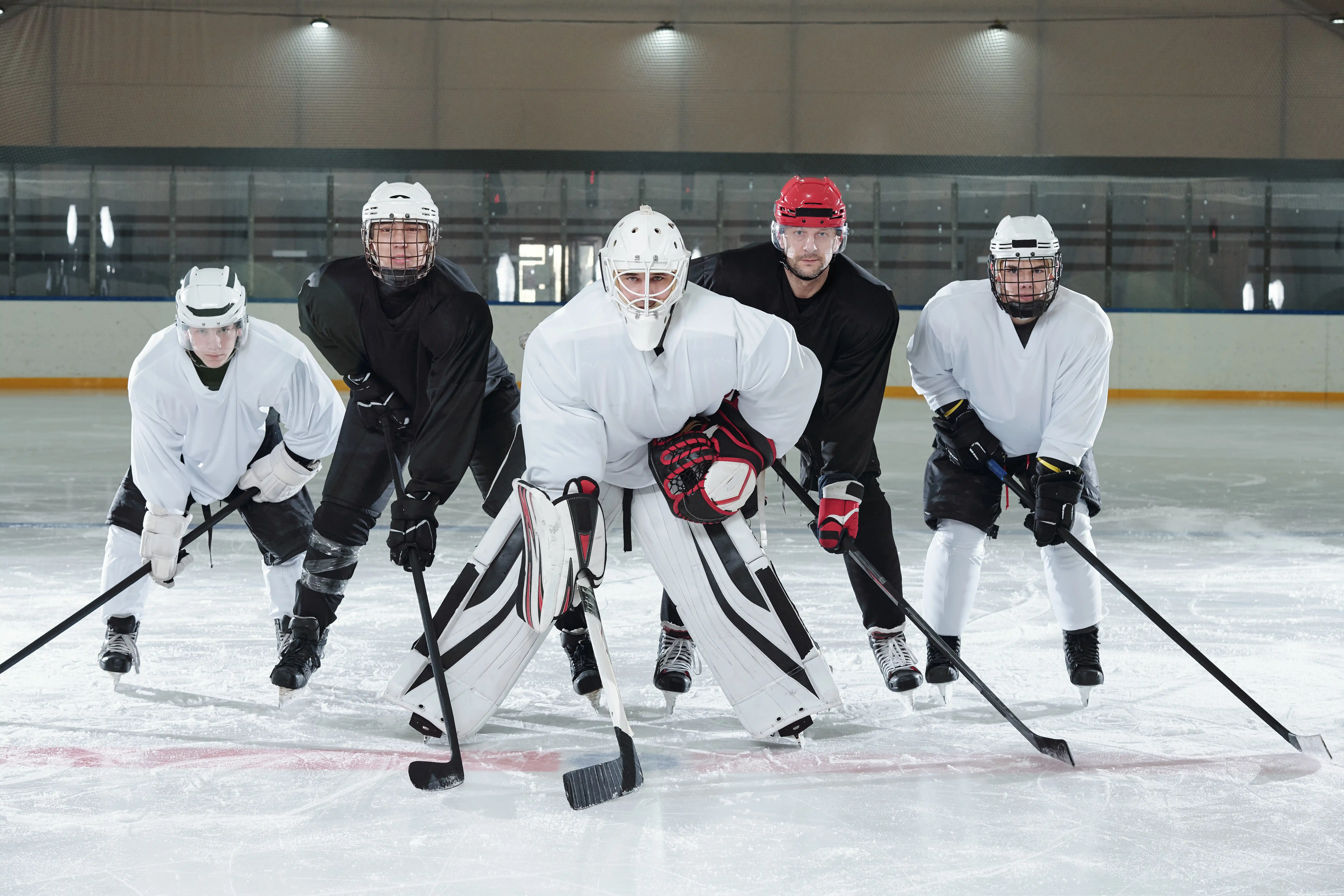 professional-hockey-players-gloves-skates-helmets-bending-forwards-while-standing-ice-rink-training-before-play-stadium